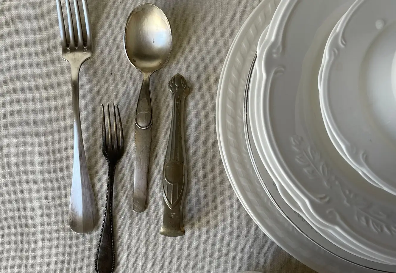 Silverbestick, silversmycken och silvermynt upplagda på vitt linne